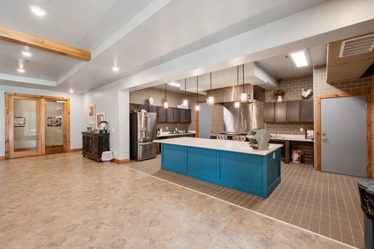 A spacious modern kitchen with a blue island, stainless steel appliances, and pendant lighting.