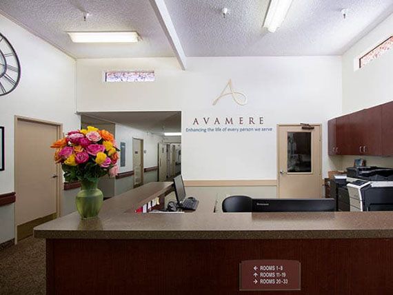 A reception desk with a computer and a vase of colorful flowers in an office setting.