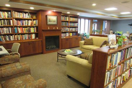 A cozy library with bookshelves, a fireplace, and comfortable seating.