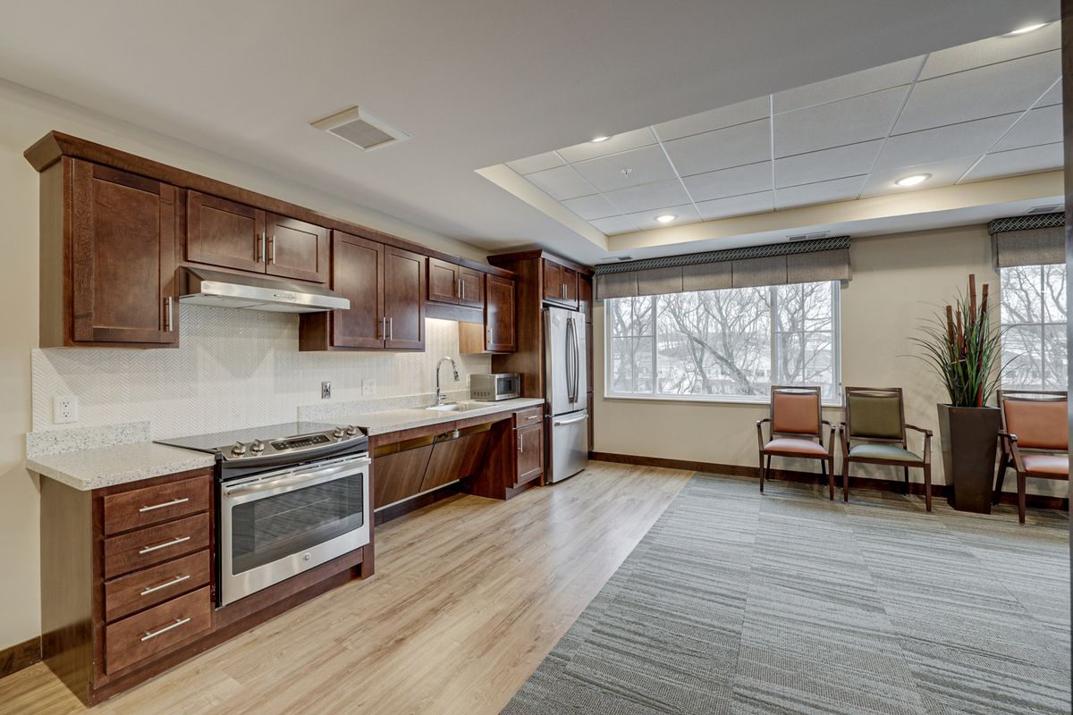 A modern kitchen with wood cabinets, an oven, and large windows.