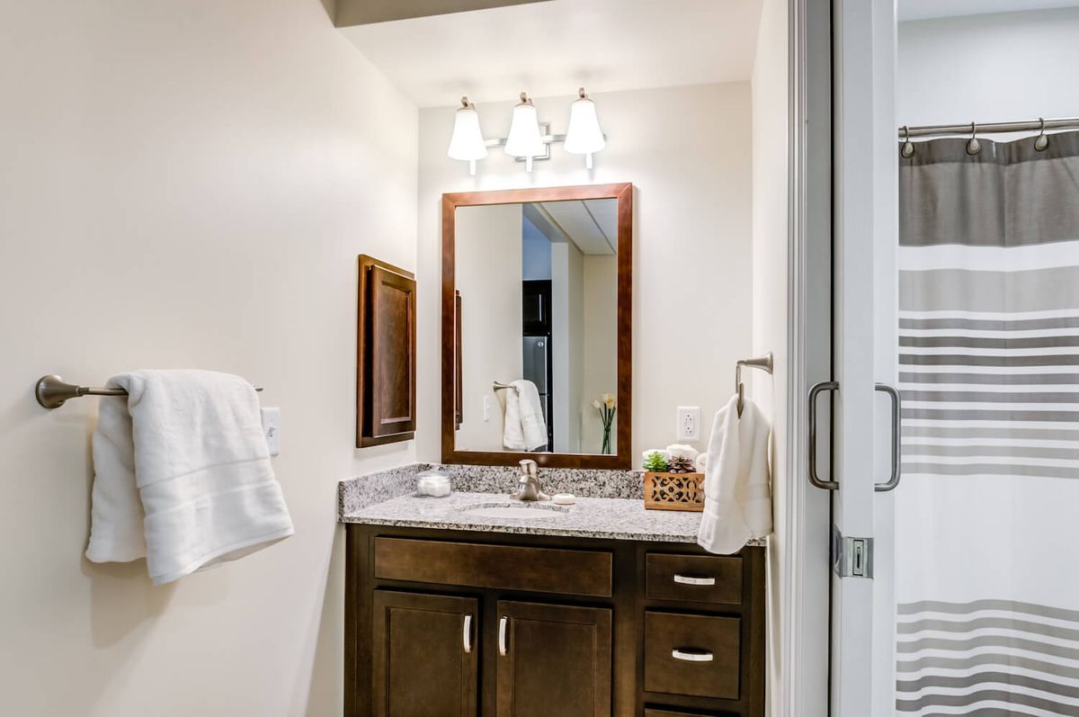 A stylish bathroom with a wooden vanity, mirror, and elegant lighting.