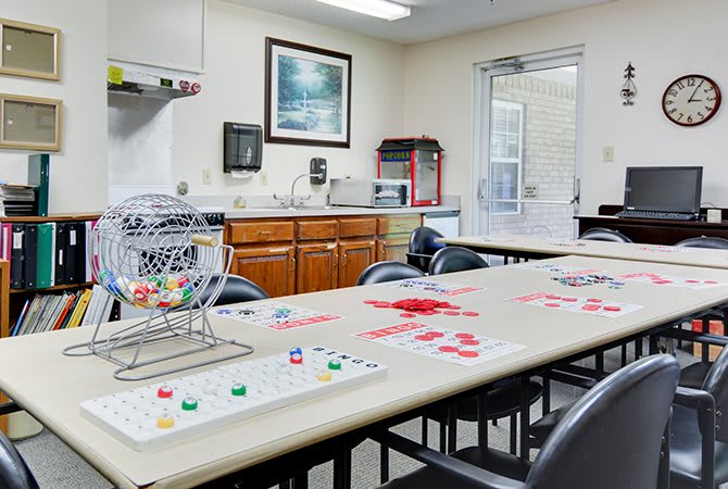 A cozy game room set up for bingo, featuring tables and chairs, a kitchenette, and organized bingo supplies.
