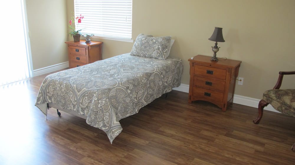 A minimalist bedroom with a single bed and wooden furniture.