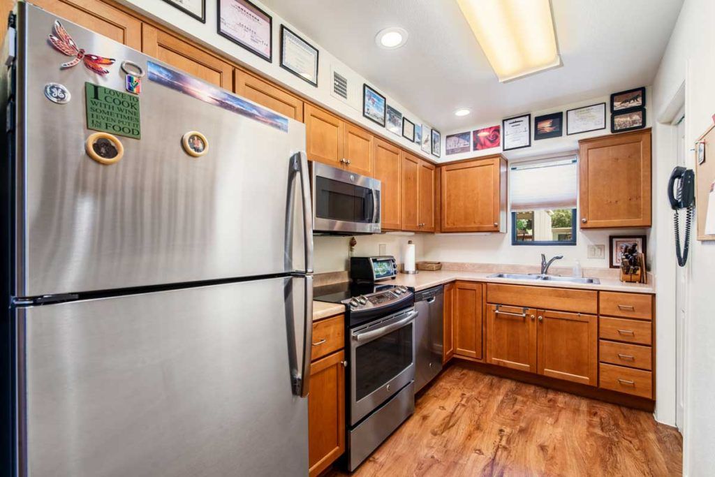 A modern kitchen with stainless steel appliances and wooden cabinets, decorated with framed pictures on the walls.