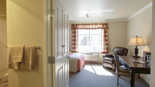 A cozy bedroom with a large window and comfortable furnishings.