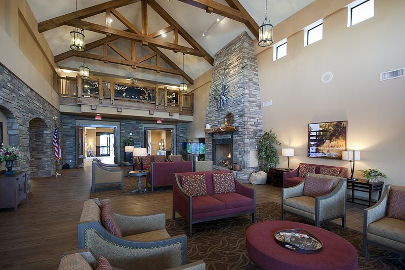 A spacious lobby with a modern design featuring comfortable seating, a stone fireplace, and wooden beam high ceilings.