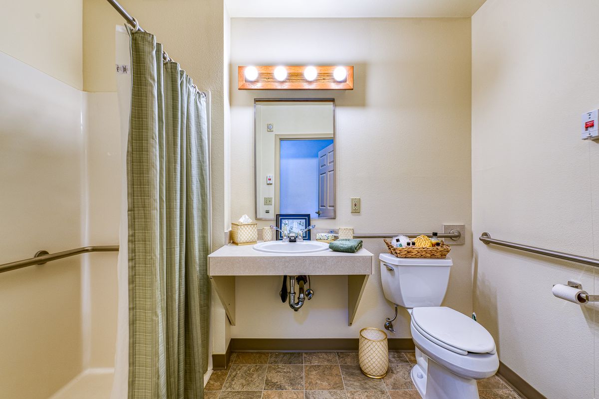 A bathroom with a sink, mirror, toilet, and shower curtain.