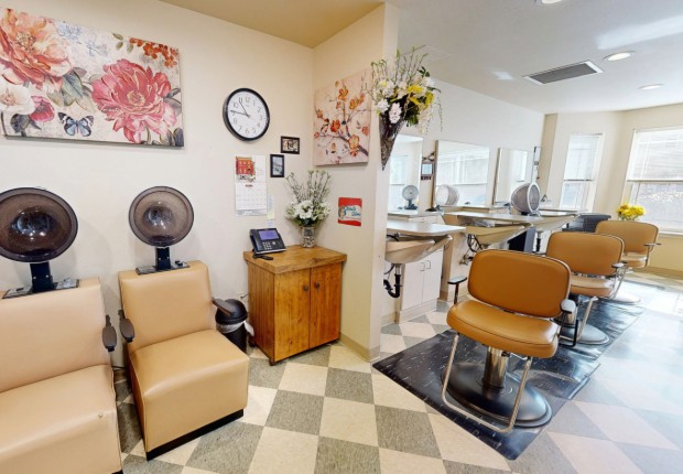 A cozy hair salon interior featuring styling chairs, a mirror, and a hair dryer station.