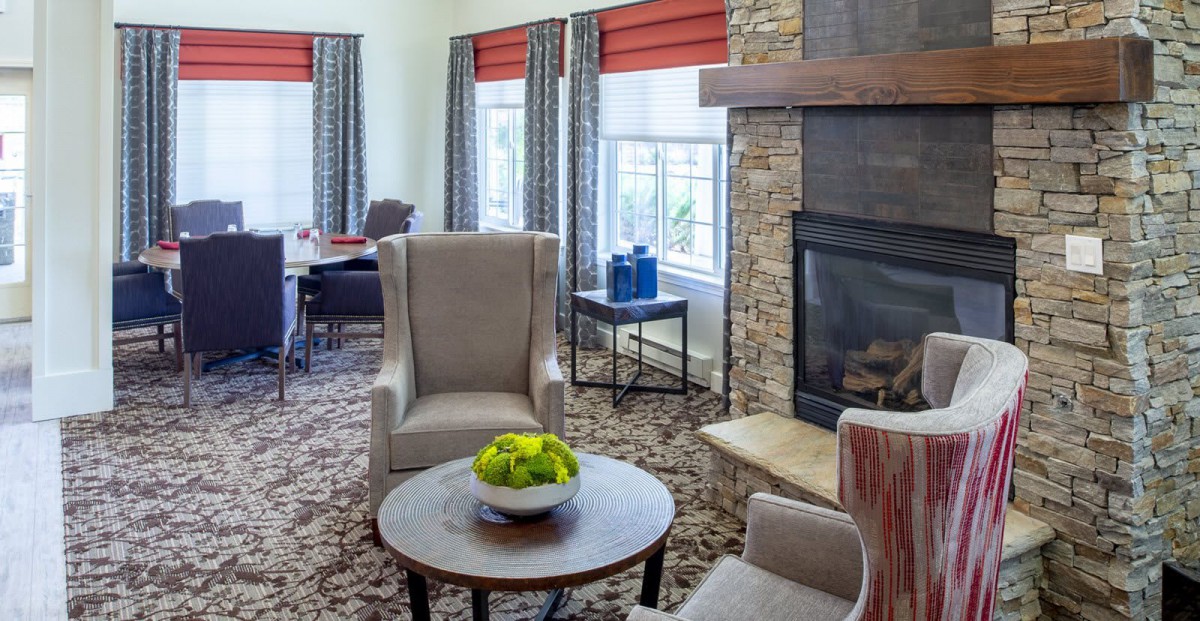 A cozy living room area with armchairs, a fireplace, and a coffee table decorated with green apples.