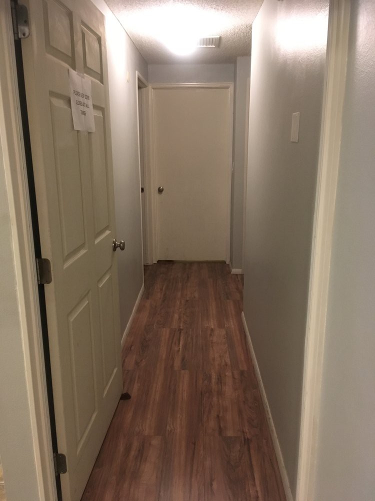 A narrow hallway with wooden flooring and multiple doors.