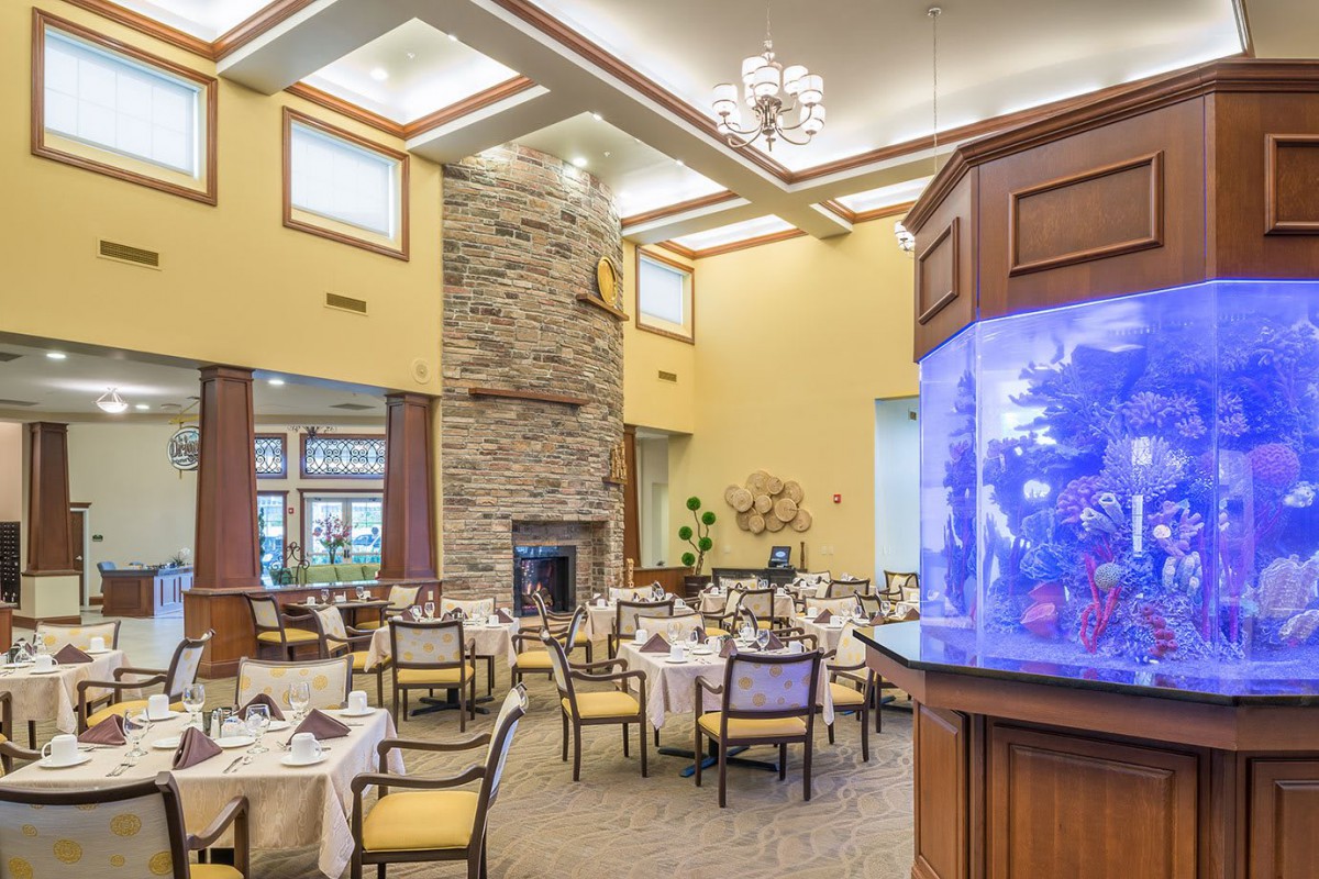 A modern dining area with elegant furnishings and a large aquarium centerpiece.
