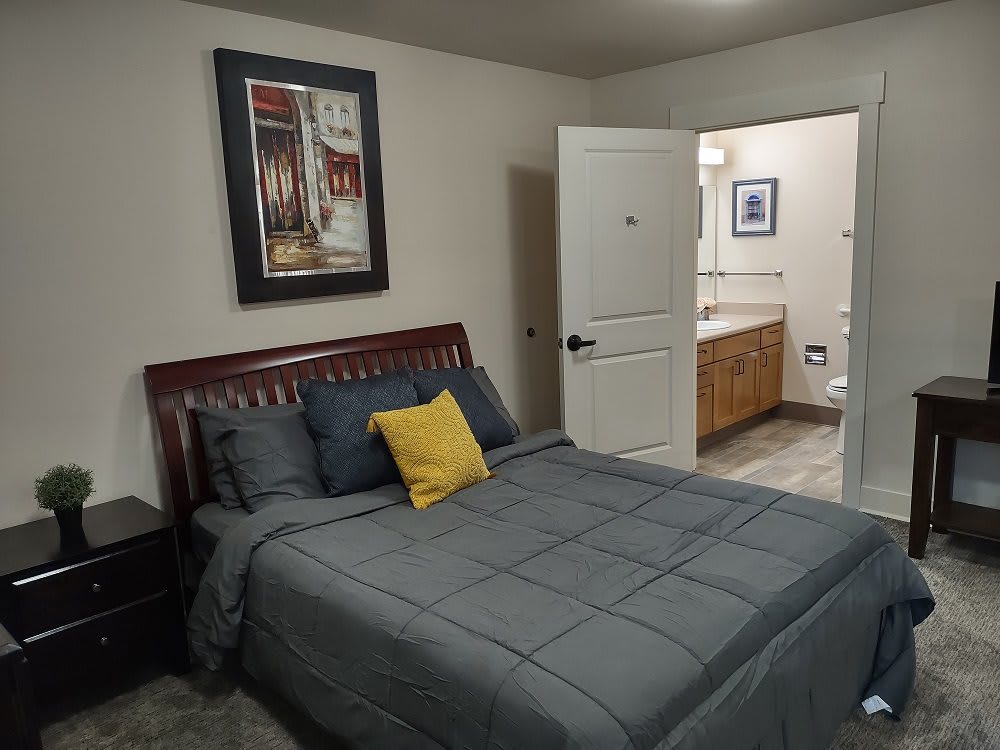 A cozy bedroom with a neatly made bed and an adjoining bathroom.