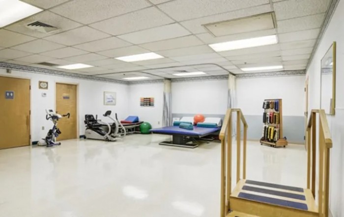 A physical therapy room equipped with exercise machinery and a therapy bed.