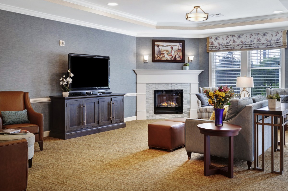A cozy living room with a fireplace and television, featuring comfortable seating and elegant decor.