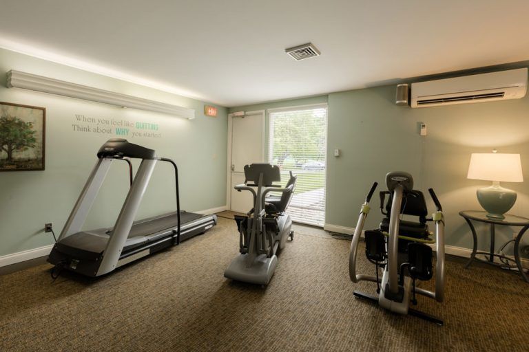 A small gym with exercise equipment including a treadmill and stationary bikes.