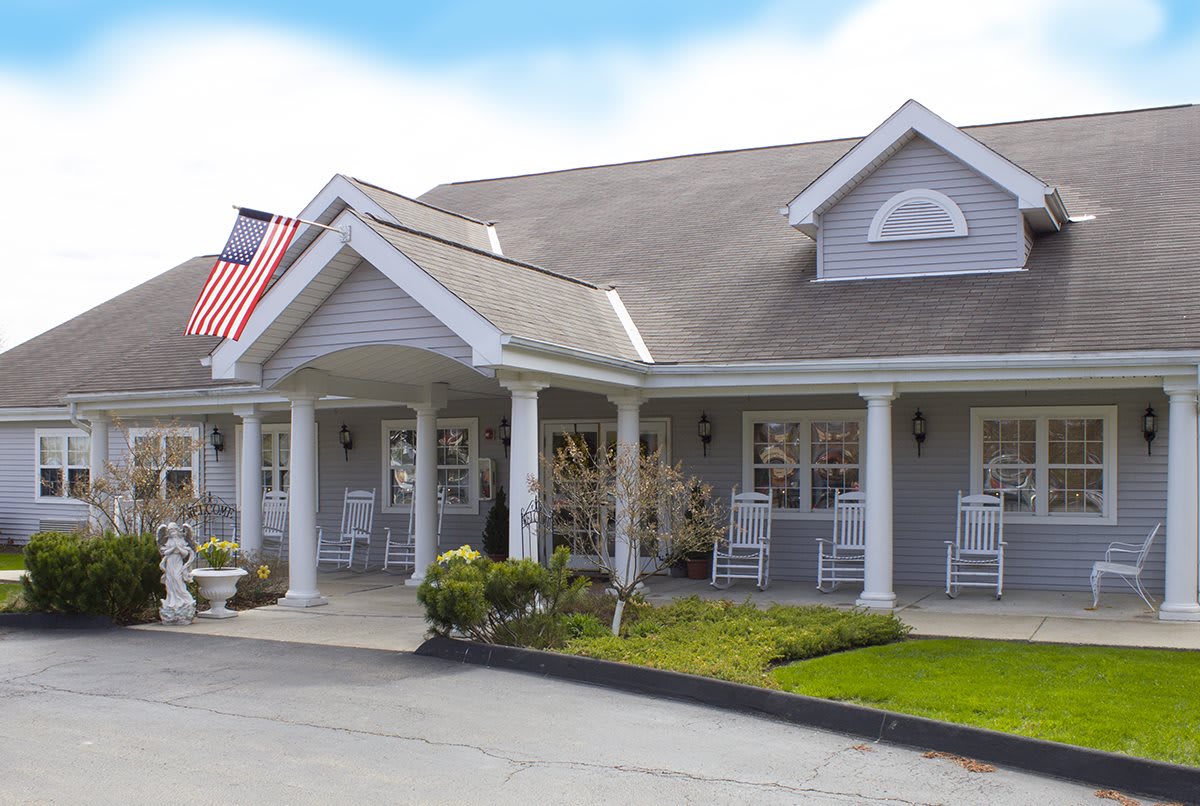 A quaint building with a porch and rocking chairs, adorned with an American flag.