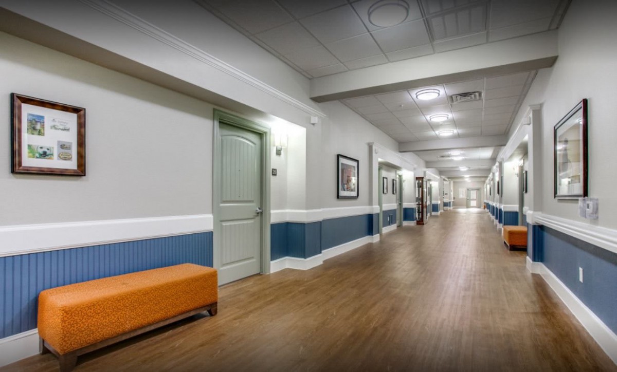 A modern hallway with wooden flooring, benches, and doors along the sides.
