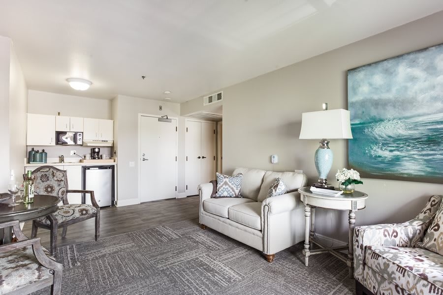 A modern living room with neutral tones, featuring a cozy sofa, stylish lamp, artwork on the wall, and contemporary furniture.