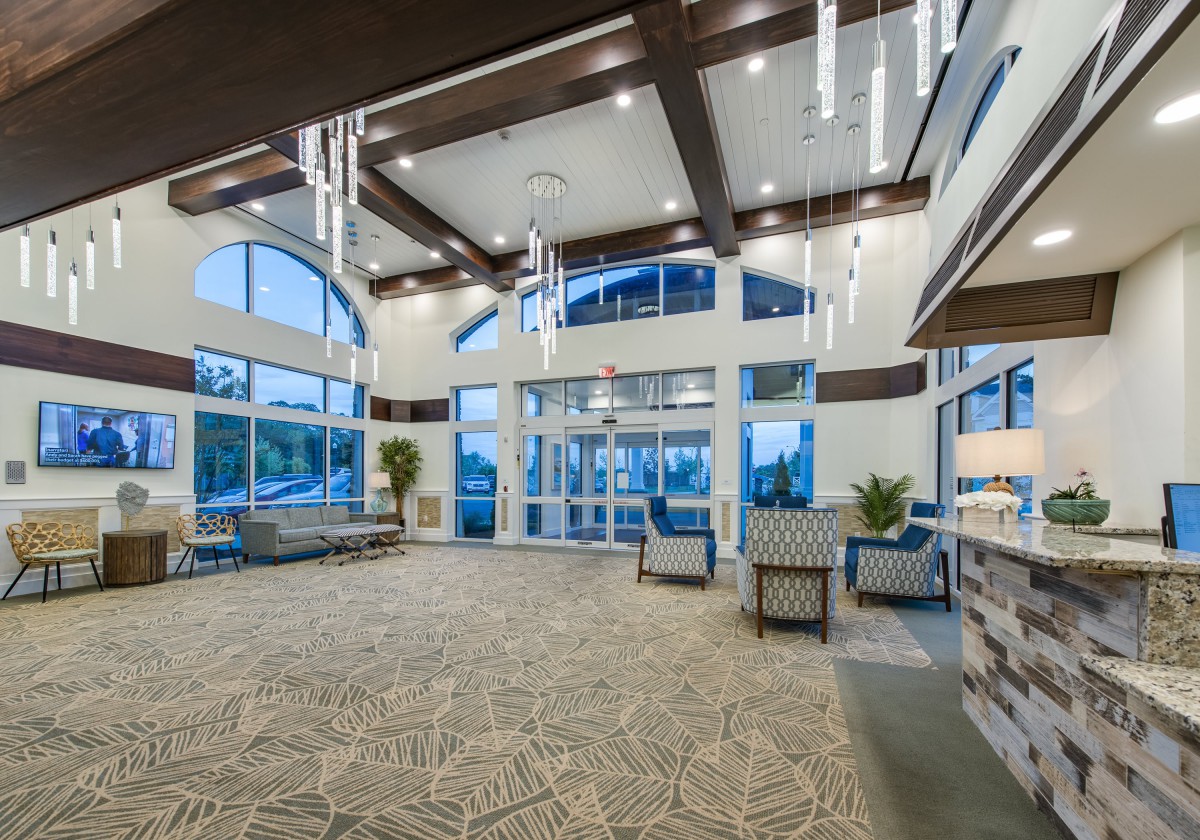 A spacious and modern lobby with elegant chandeliers and large windows.