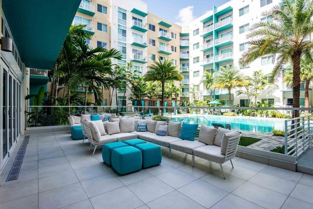 Modern apartment complex with a stylish outdoor pool area and patio seating.