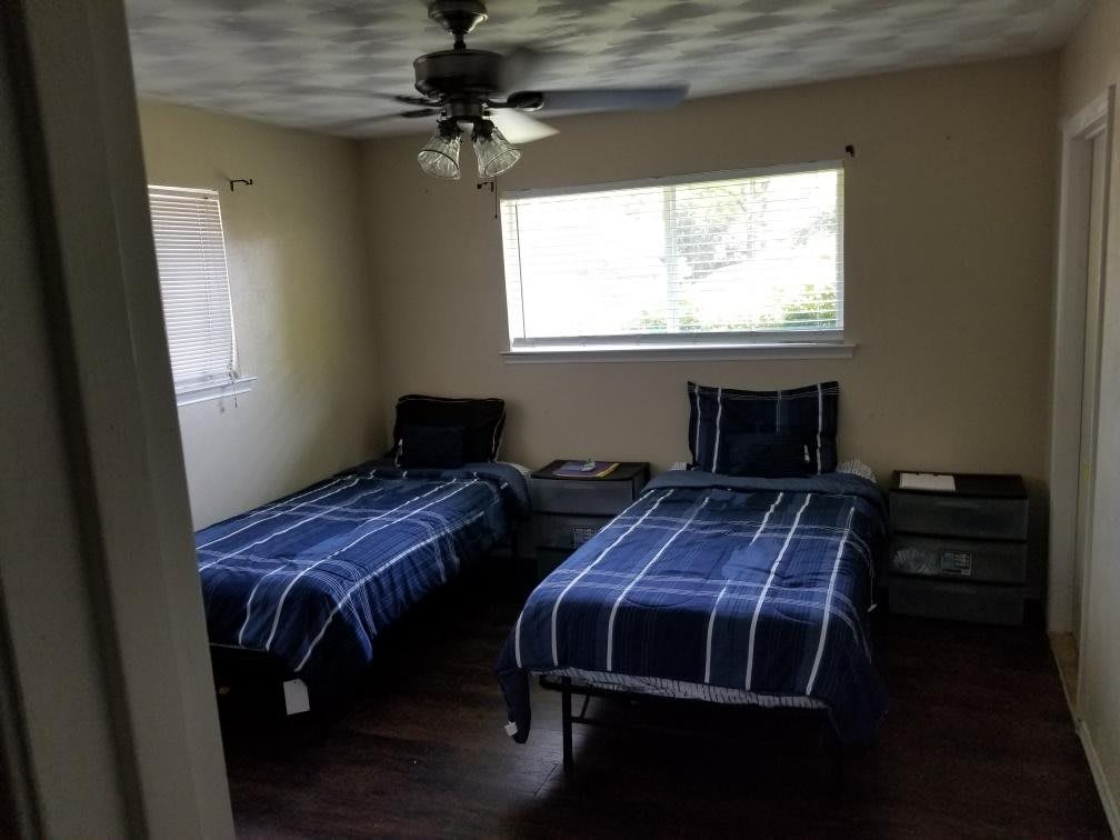 A bedroom with two twin beds, featuring blue plaid bedding and a window letting in natural light.