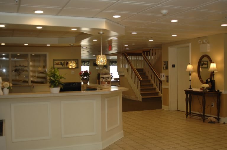 A well-lit hotel lobby with a reception desk and stairs leading upward.