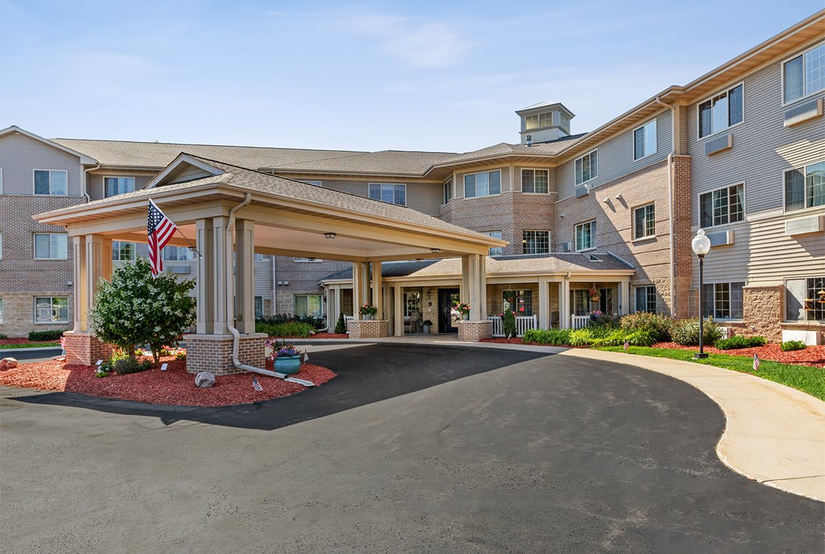 A hotel entrance with a covered driveway and well-maintained landscaping.