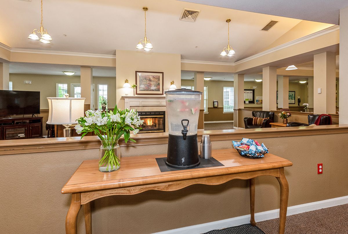 A welcoming reception area featuring a wooden table with flowers, a water dispenser, and snacks.