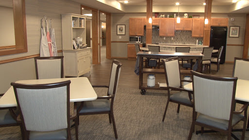 A modern dining area featuring wooden furniture and a spacious kitchen in the background.