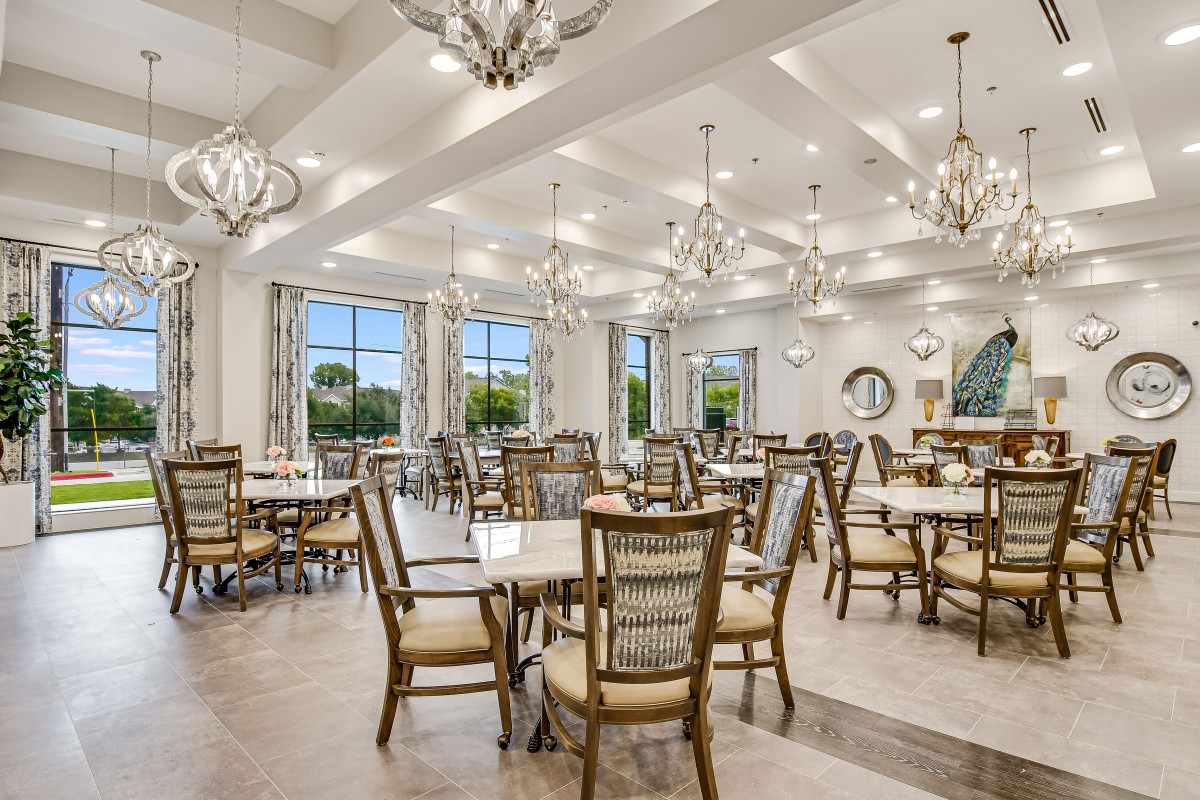 Elegant dining room with chandeliers and ample natural light.