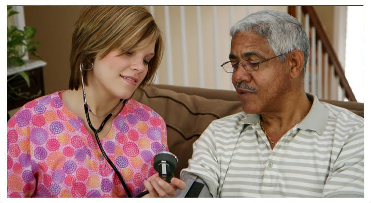 A nurse checks the blood pressure of an elderly patient at home.