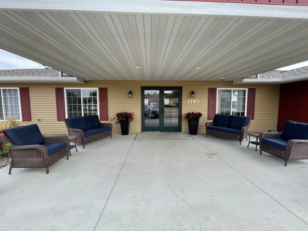 The entrance of a building with outdoor seating and decorative plants.