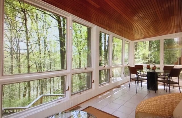 A modern sunroom with large windows offering a scenic view of nature.