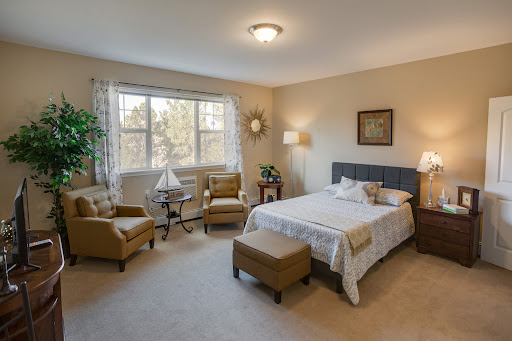 A cozy and elegantly decorated bedroom featuring a comfortable bed, two armchairs, and natural light streaming through the window.
