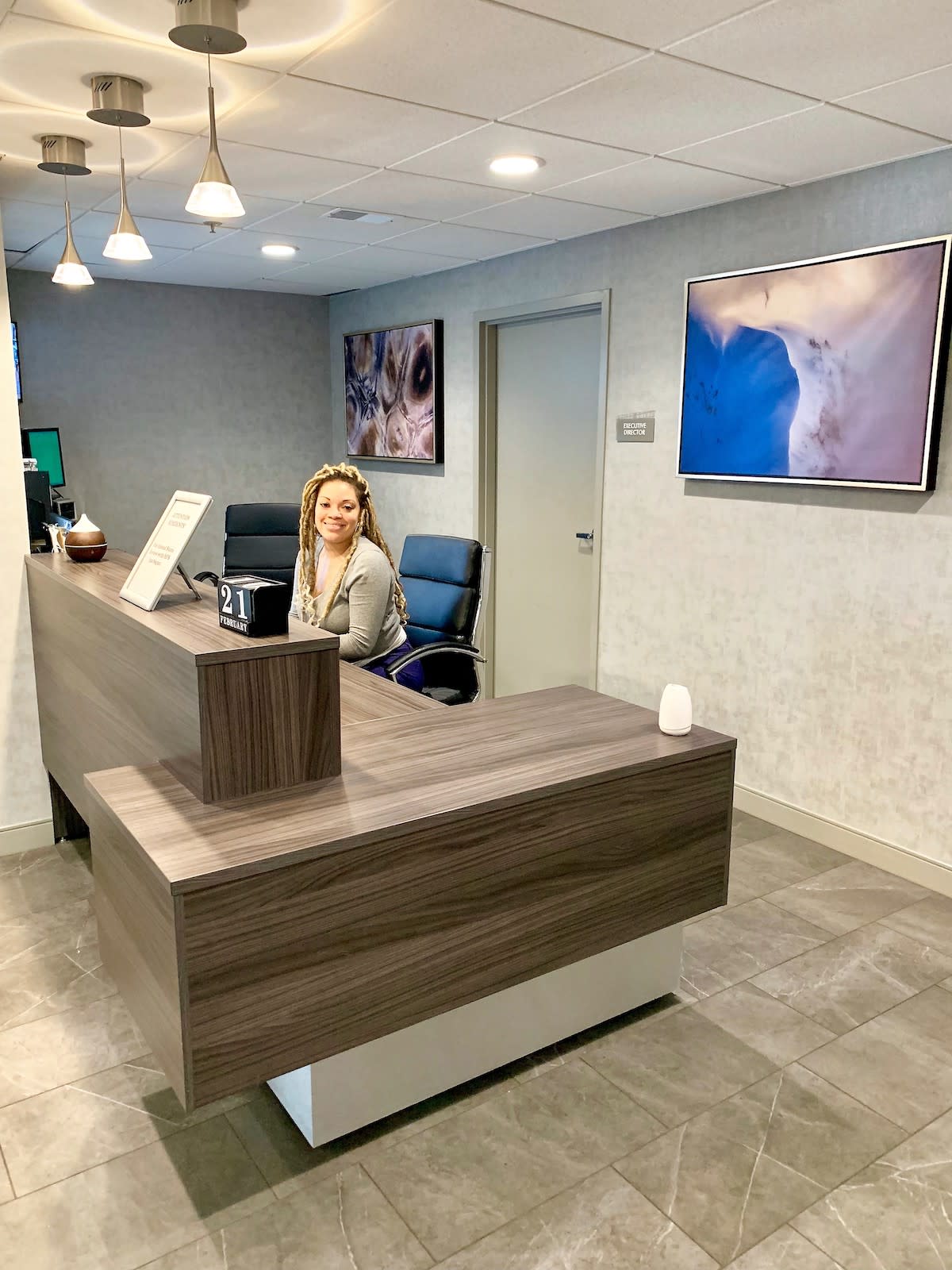 A modern office reception area with a person sitting at the desk.