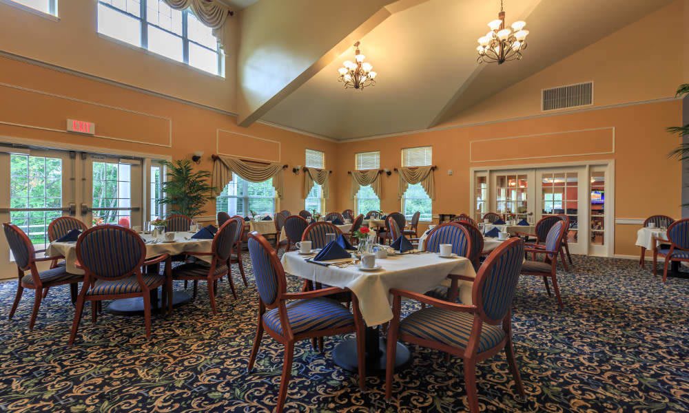 An elegant dining room setup with neatly arranged tables and chairs, decorated with chandeliers.