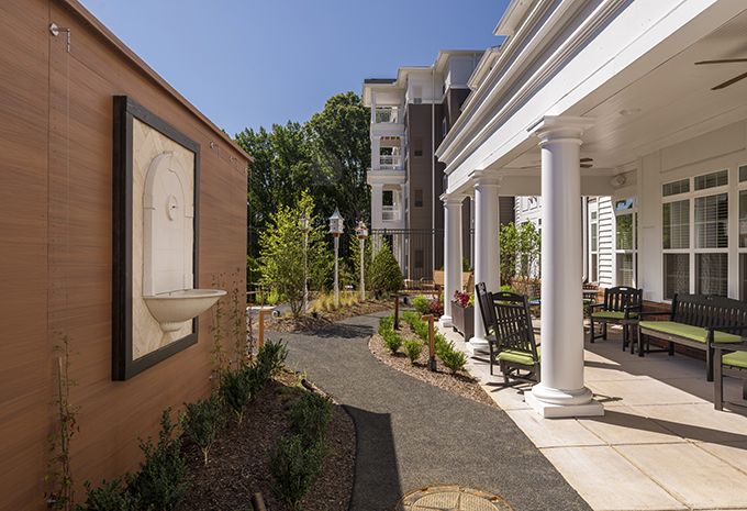A well-landscaped outdoor area featuring a pathway, columns, and a patio adjacent to buildings.