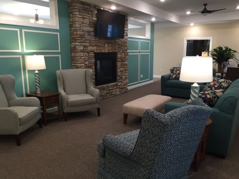 A cozy living room with modern decor, featuring a fireplace, armchairs, a sofa, and a television.