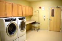 A laundry room with a washing machine, dryer, cabinets, and a laundry basket.