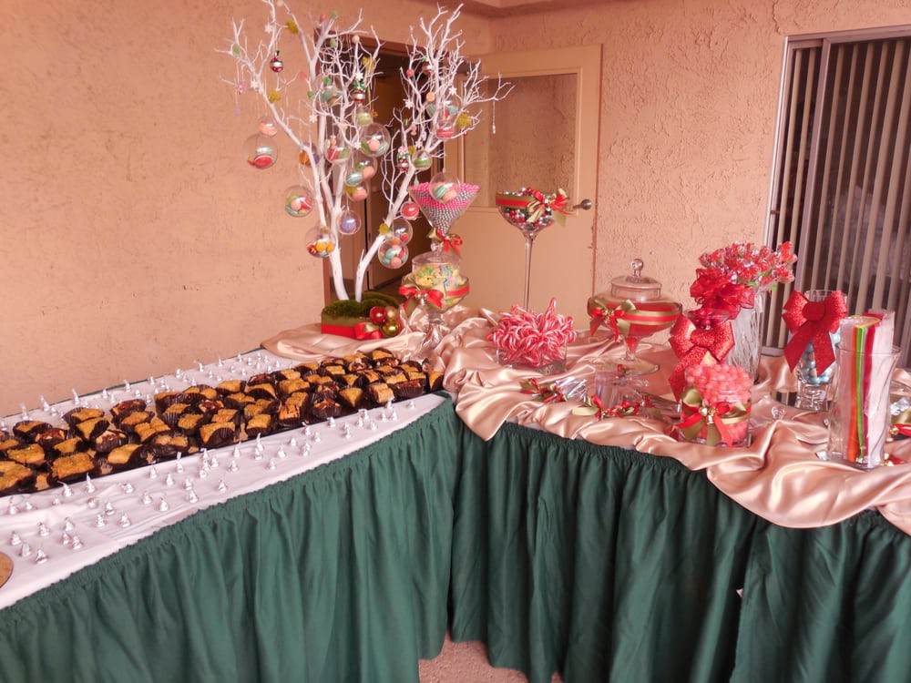 A festive buffet table decorated with a green tablecloth, featuring a variety of foods and holiday-themed decorations.