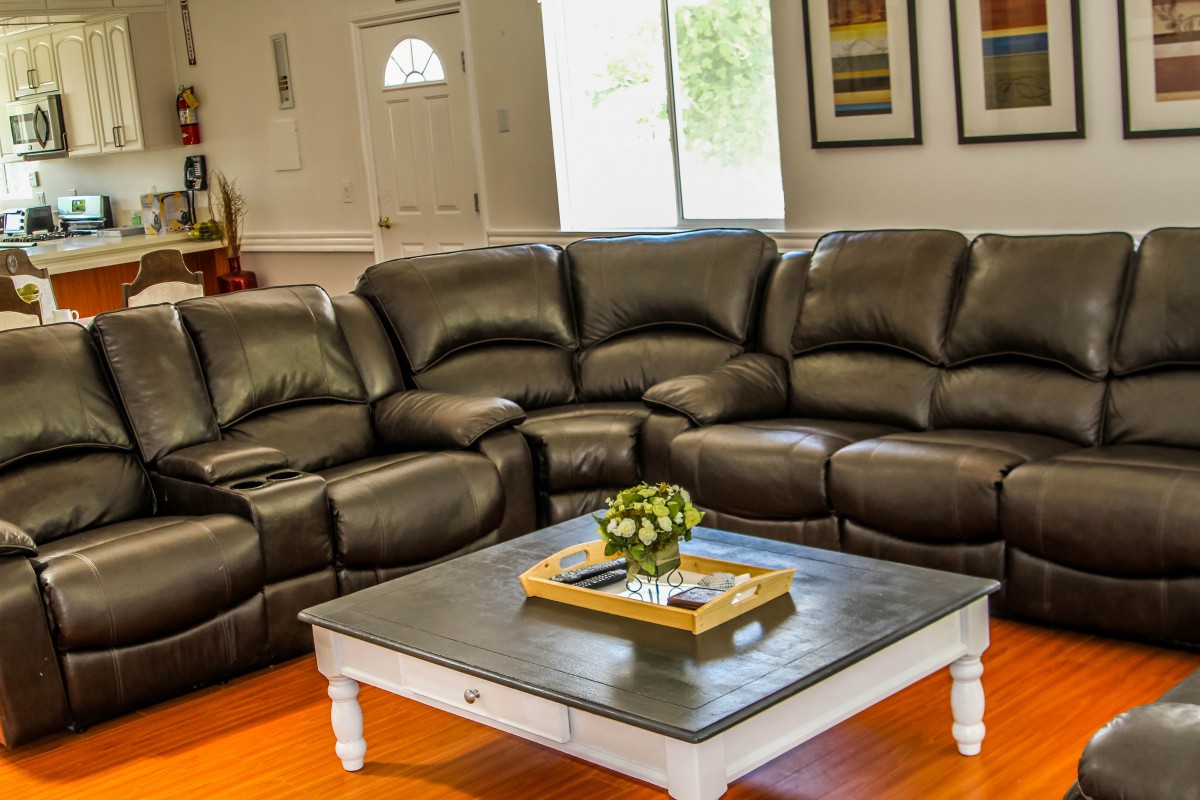 A cozy living room with a large leather sectional sofa and a wooden coffee table.
