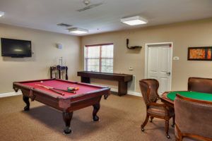 A cozy game room featuring a pool table, poker table, and classic decor.