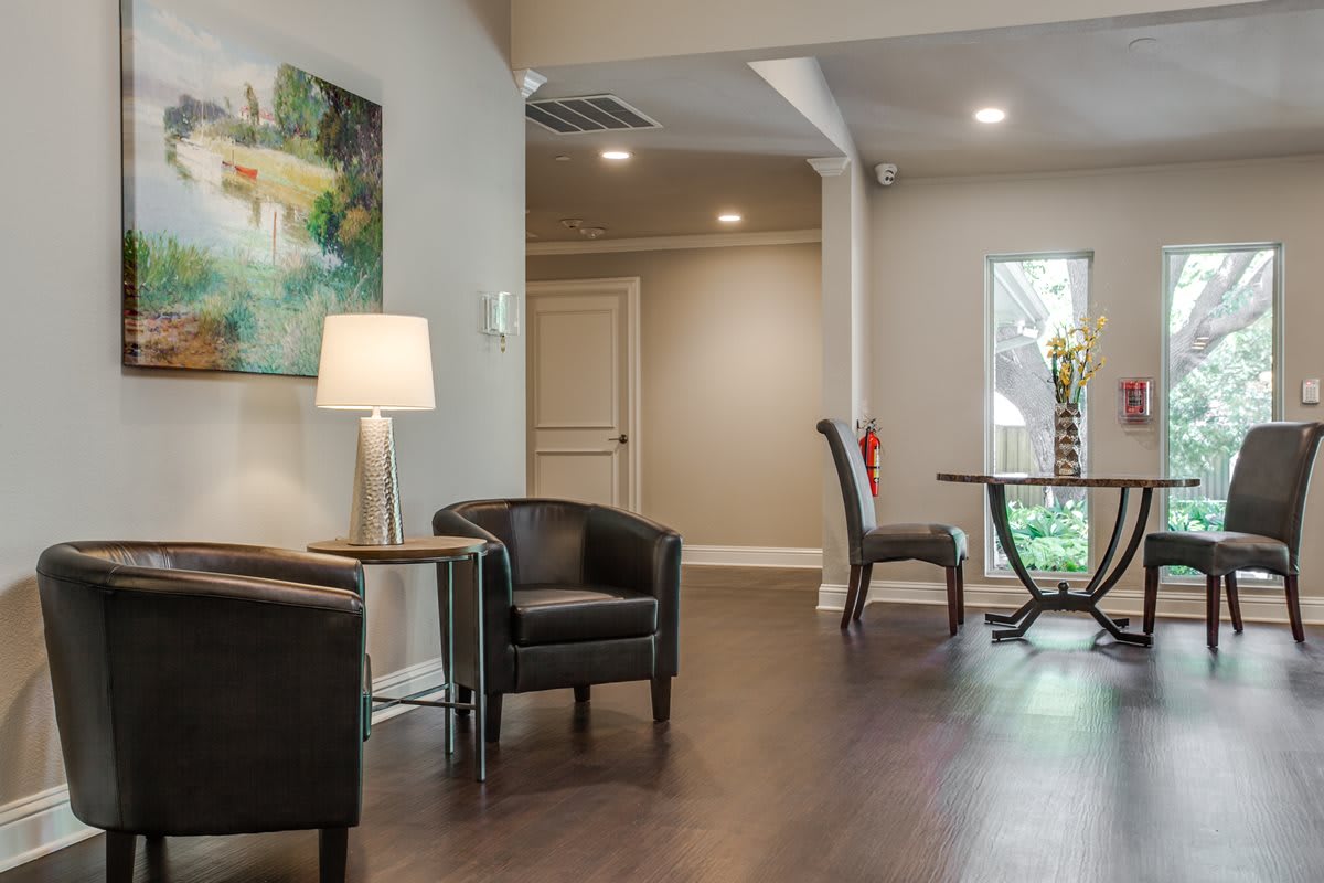 A modern lobby area featuring comfortable armchairs, a lamp, and decorative artwork.