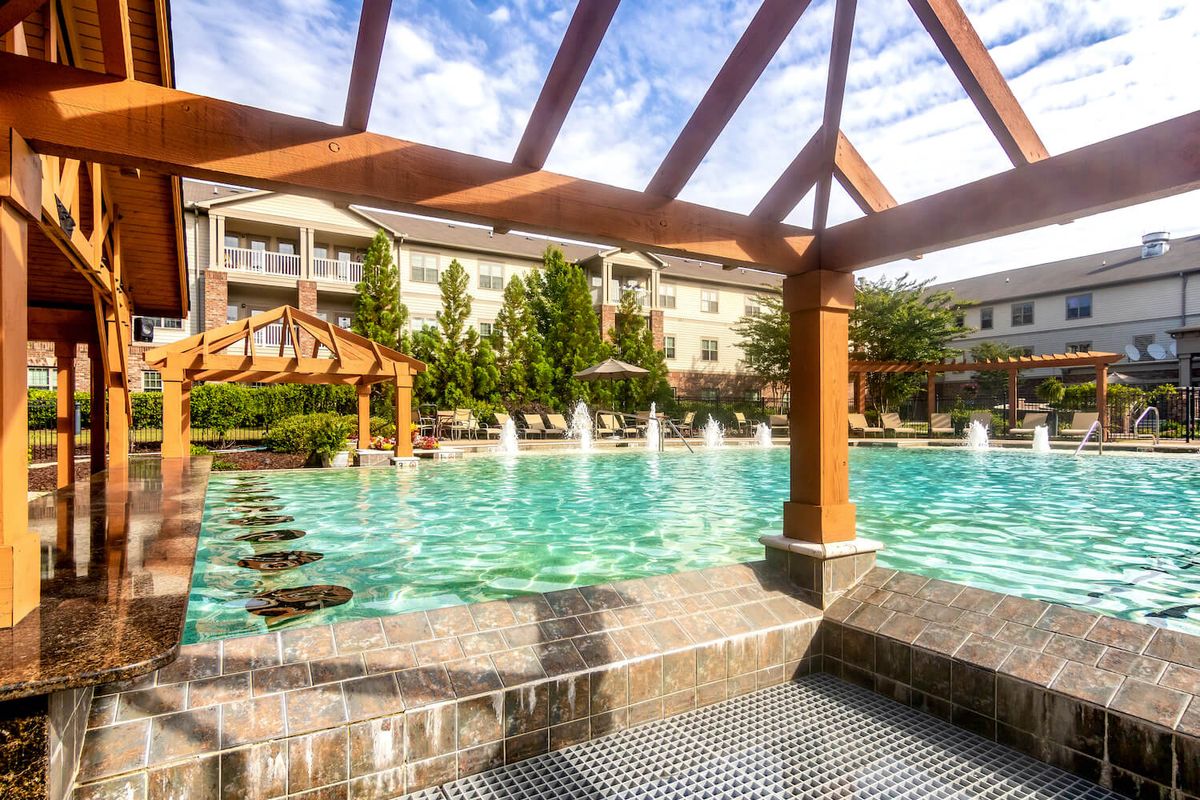 Luxurious apartment complex with a large outdoor pool surrounded by landscaped gardens.