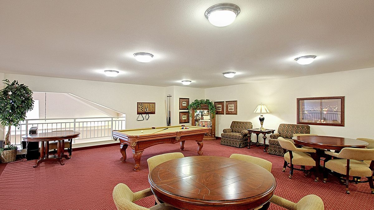 A spacious game room featuring a pool table, comfortable seating, and warm lighting.