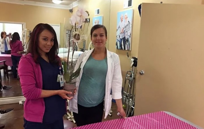 Two healthcare professionals posing in a clinic setting with an orchid.