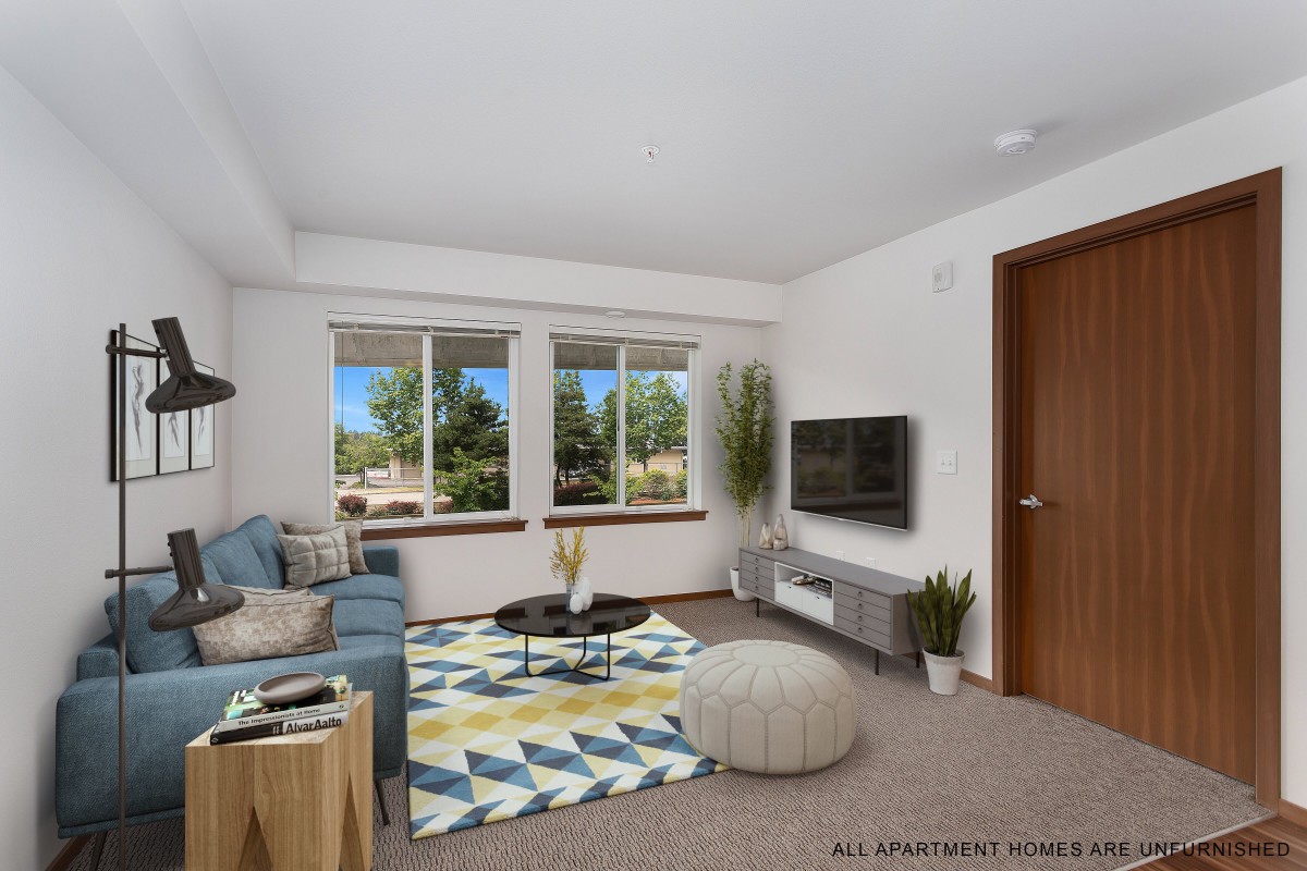 A modern living room with a cozy sofa, vibrant rug, and a flat-screen TV mounted on the wall.