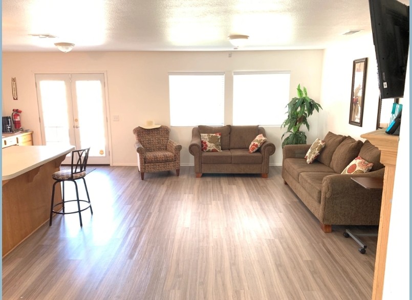 A spacious living room with two sofas, an armchair, and hardwood flooring.