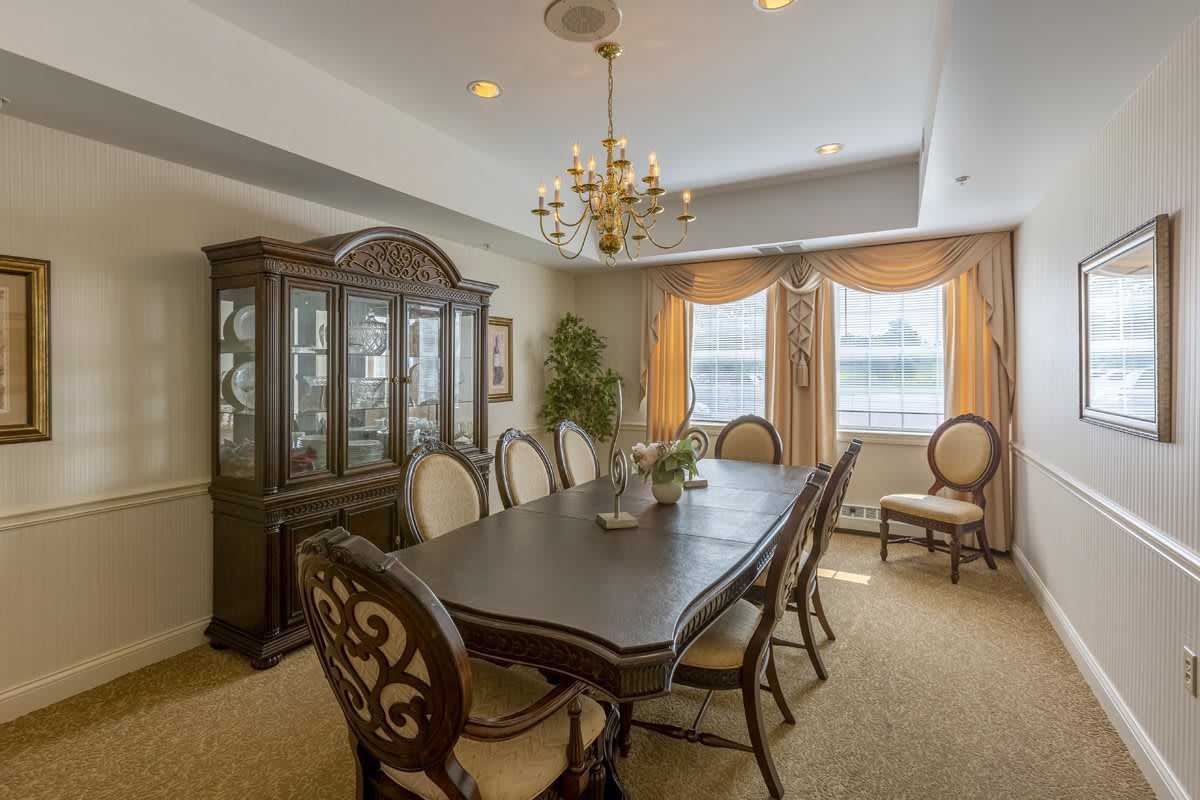 A traditional dining room with a large table, chairs, and a chandelier.