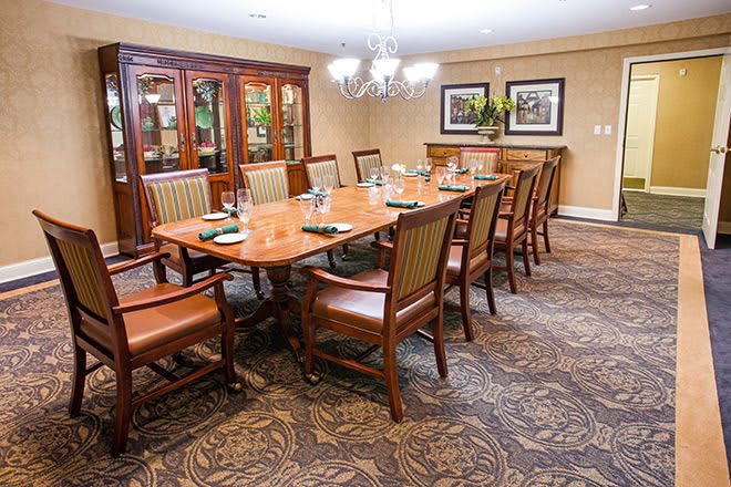 A well-furnished dining room featuring a large table surrounded by chairs, with a decorative chandelier above.